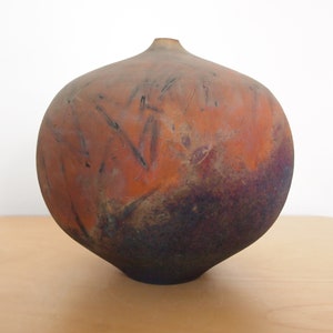 May include: A round, brown ceramic vase with a dark brown glaze. The vase has a wide mouth and a narrow base.