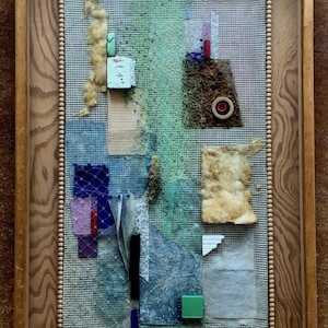 Puede incluir: Una obra de arte mixta enmarcada con una variedad de texturas y colores, incluyendo verde, azul, marrón y blanco. La obra está hecha de diferentes materiales, como tela, papel e hilo. La obra está enmarcada en un marco de madera con un borde de cuentas. El número 25 está escrito en la esquina inferior derecha del marco.