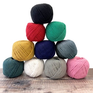 May include: A collection of ten balls of yarn in various colors, including black, red, green, yellow, blue, gray, white, and pink. The balls of yarn are arranged in a triangular shape.