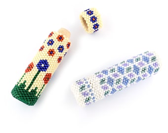 May include: Three beaded containers with different patterns. One is a ring, one is a short cylinder, and the other is a longer cylinder. The ring is white with blue and orange beads. The short cylinder is white with green, orange, and blue beads. The long cylinder is white with blue, green, and purple beads.