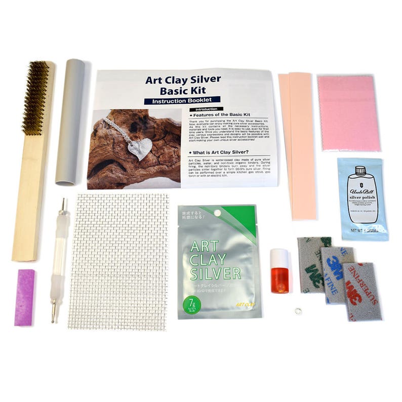 May include: Art Clay Silver Basic Kit with instructions, tools, and materials for making jewelry. The kit includes a silver clay bar, a polishing cloth, a sanding sponge, a brush, a tool, a small bottle of silver polish, and a small bottle of liquid. The kit also includes a small piece of silver jewelry.