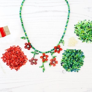 Pode incluir: Um kit de colar de contas com contas vermelhas e verdes, com um design floral. O kit inclui um carretel de fio, fechos e várias bolsas de contas.