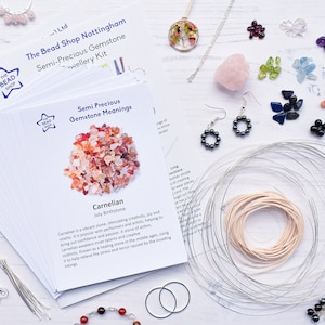 May include: A collection of jewelry-making supplies and components, including gemstones, wire, and printed cards. The cards feature text about semi-precious gemstones. Various finished jewelry pieces are also visible, such as necklaces and earrings.