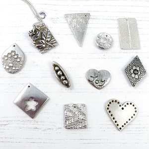 May include: A collection of 10 silver metal charms with various designs, including a flower, a heart, a pea pod, a star, and a rose. The charms are all made of silver metal and have a textured finish.