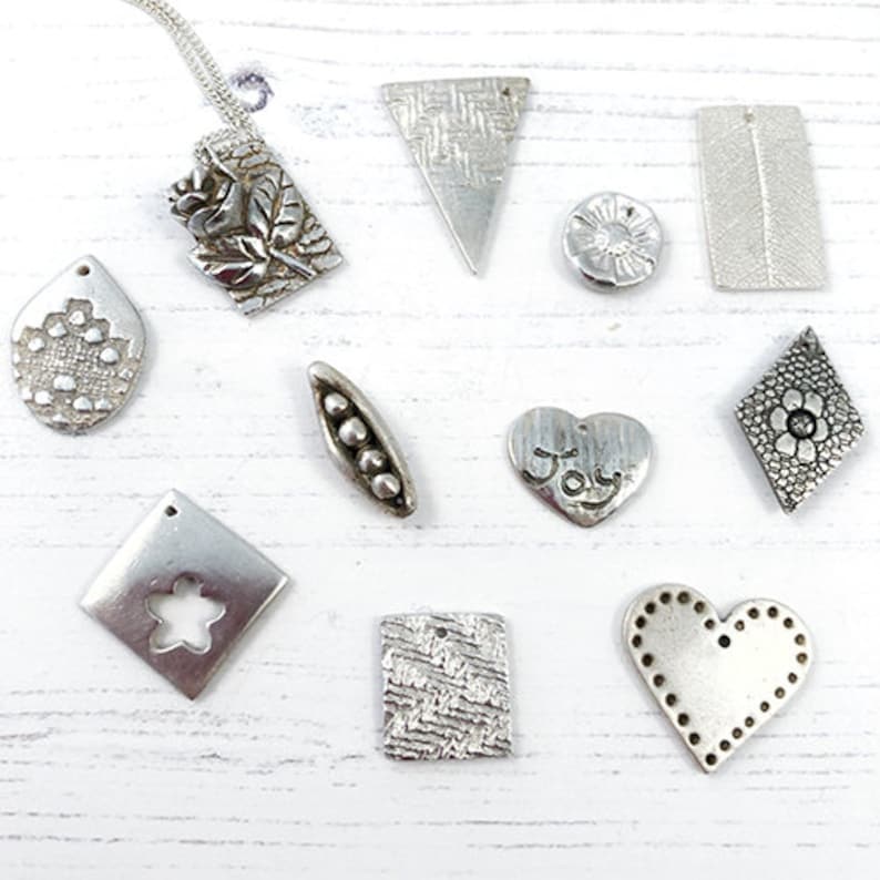 May include: A collection of 10 silver metal charms with various designs, including a flower, a heart, a pea pod, a star, and a rose. The charms are all made of silver metal and have a textured finish.
