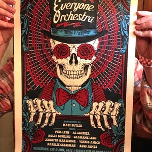May include: A concert poster for Everyone Orchestra, conducted by Matt Butler, with Phil Lesh, Al Schnier, Holly Bowling, Grahame Lesh, Jennifer Hartswick, Vinnie Amico, Natalie Cressman, and Ross James. The poster features a skull wearing a top hat and bow tie, with red roses for eyes. The concert is scheduled for December 1st and 2nd, 2013 at Terrapin Crossroads.