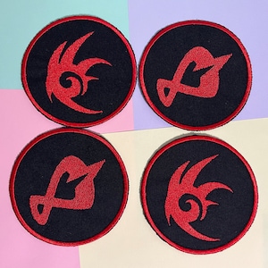 Könnte beinhalten: Vier runde, schwarze Aufnäher mit rot gestickten Designs. Jeder Aufnäher hat einen roten Rand. Die Designs sind abstrakt, mit einer flammenartigen oder stilisierten Form. Die Aufnäher sind quadratisch auf einem mehrfarbigen Hintergrund angeordnet.