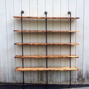 May include: A five-shelf industrial-style shelving unit made of black metal pipes and reclaimed wood planks. The shelves are mounted to a white wall.