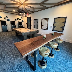 May include: A room featuring a pool table, a long wooden bar with stools, and abstract art on the walls. The room has a patterned carpet and a decorative ceiling with a chandelier.