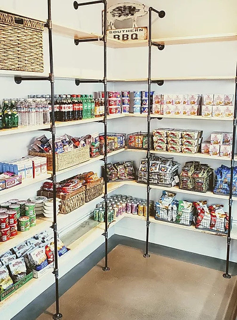 May include: A corner pantry with black metal pipe shelving stocked with canned goods, snacks, and beverages. The shelves are labeled "Southern BBQ".