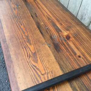 May include: A rustic wooden shelf with black metal pipe supports. The wood has a natural, distressed finish with visible grain patterns.