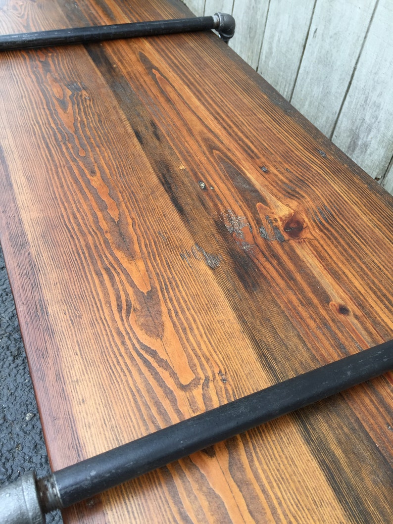 May include: A rustic wooden shelf with black metal pipe supports. The wood has a natural, distressed finish with visible grain patterns.