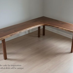 May include: An L-shaped desk made of dark brown wood with a natural live edge along the front and side surfaces. The desk features a smooth, polished top surface and is supported by six straight, rectangular wooden legs. Text reads: Design render only for inspiration: Actual handcrafted desk will be unique.