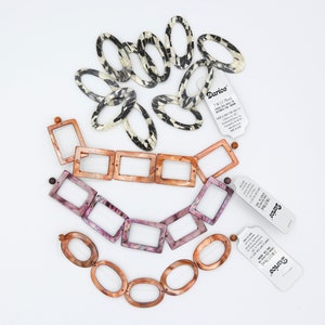 May include: Three sets of plastic hair clips in different colors and patterns. The first set is black and white, the second set is pink and white, and the third set is brown. The clips are all oval shaped and have a glossy finish.