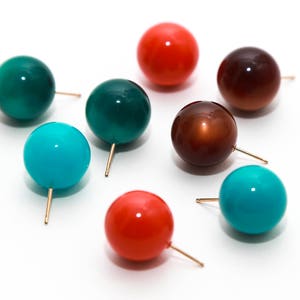 May include: Assortment of colorful round earrings with gold posts. The earrings are in shades of teal, turquoise, brown, and orange.