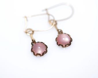 May include: A pair of gold earrings with pink gemstone accents. The earrings have a delicate, ornate design.