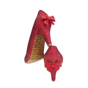 Könnte beinhalten: Ein Paar rote Glitzer-High Heels mit einer Schleife an der Vorderseite jedes Schuhs.