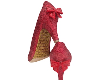 May include: A pair of red glitter high heels with a bow on the front of each shoe.