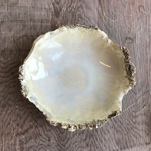 May include: A white ceramic bowl with a rough, textured rim. The bowl has a slightly iridescent glaze and is perfect for serving small snacks or holding jewelry.