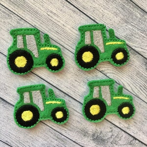 May include: Four green felt tractor appliques with black wheels and yellow centers. The tractors have gray details and are perfect for crafting projects.