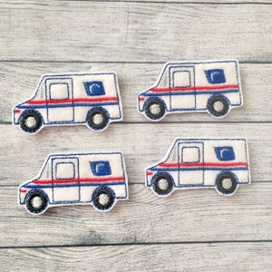 May include: Four white felt mail truck appliques with blue and red details. The trucks have a single window and a red stripe across the side.