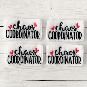May include: Four white felt patches with red hearts and black embroidery that reads "chaos coordinator".