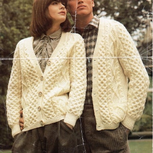 May include: Two people wearing white knitted cardigans with cable knit patterns. The cardigan has a V-neck and buttons down the front. The cardigan is 32 to 42 inches in size.