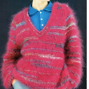 May include: A pink fuzzy knit sweater with a V-neck and grey stripes. The sweater is being worn by a person wearing sunglasses and a blue collared shirt. The text "QUICK TO KNIT - ONE BIG AND ONE NORMAL SIZE NEEDLE" is at the bottom of the image.