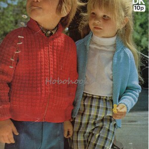 Könnte beinhalten: Zwei Kinder tragen gestrickte Strickjacken. Der Junge trägt eine rote Strickjacke mit Reißverschluss und das Mädchen trägt eine hellblaue Strickjacke. Das Mädchen hält eine gelbe Blume. Das Bild enthält den Text "Sirdar 4159 DK 10p 2/4 years".