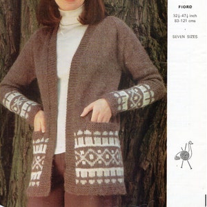 May include: A brown cardigan with white geometric patterns on the sleeves and pockets. The cardigan is open at the front and has a V-neck. The model is wearing a white turtleneck shirt underneath. The cardigan is 32 1/2 to 47 1/2 inches long, or 83 to 121 centimetres. The pattern is called "Fiord" and is available in seven sizes. The image also includes the text "3128 Emu".