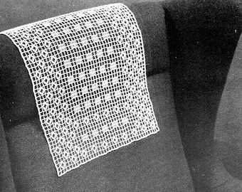 Puede incluir: Una funda de respaldo de silla de crochet blanco con un patrón geométrico. La funda está colocada en una silla gris oscuro.