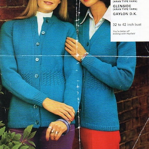 Può includere: Due donne indossano cardigan di lana blu con chiusura a bottoni. I cardigan hanno un motivo testurizzato e sono di un colore turchese brillante. Le donne sono in piedi davanti a un muro di mattoni. Il testo sulla pagina dice "Knit into fashion-with Hayfield Brig (Aran Type Yarn) Glenside (Aran Type Yarn) Gaylon D.K. 32 to 42 inch bust You're better off knitting with Hayfield"