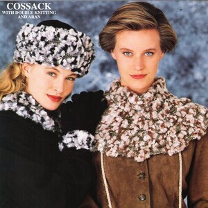 May include: Two women wearing winter accessories. The woman on the left is wearing a black coat, a white and black fur hat, and a white and black fur scarf. The woman on the right is wearing a brown suede jacket, a white and brown fur scarf, and a white crocheted bag with a white strap.