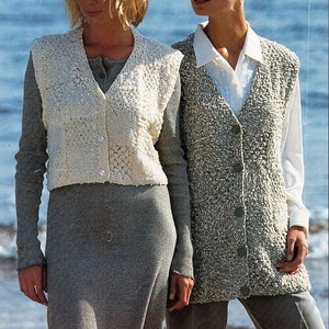 Może przedstawiać: Dwie kobiety w dzianinowych kamizelkach. Kobieta po lewej stronie ma na sobie białą kamizelkę z delikatnym wzorem i szarą spódnicę. Kobieta po prawej stronie ma na sobie szarą kamizelkę z fakturowanym wzorem i szare spodnie.