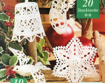 May include: Four crocheted Christmas ornaments: a bell, a stocking, a dove, and a star. The ornaments are white and hang from a wooden branch.