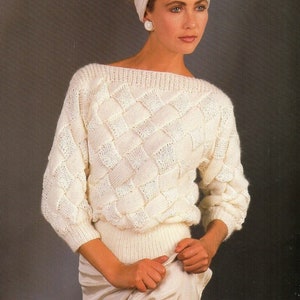 Könnte beinhalten: Ein weißer Strickpullover mit einem Zopfmuster. Der Pullover hat einen U-Boot-Ausschnitt und lange Ärmel. Das Model trägt ein weißes Stirnband.