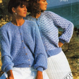 Pode incluir: Duas mulheres vestindo cardigãs de tricô azul e branco com um visual de angorá escovado. O cardigã à esquerda é azul sólido, enquanto o cardigã à direita tem um padrão de ondas branco e azul. O texto "BRUSHED DK ANGOra LOOK 30-40in (76-102cm)" está impresso no canto inferior direito da imagem. Lister Handknitting 5161 está impresso no canto superior direito.