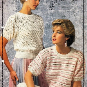 Pode incluir: Duas mulheres vestindo suéteres de crochê branco. O suéter à esquerda é branco sólido, enquanto o suéter à direita tem listras rosa. Ambos os suéteres têm um decote redondo e mangas curtas. Os suéteres são feitos com um delicado padrão de ponto aberto.