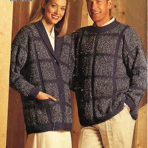 May include: A couple wearing matching navy blue knit sweaters and cardigans with a grid pattern and flecks of silver. The woman wears a cream-colored skirt, and the man wears beige pants. The word "aran" is in the top left corner.