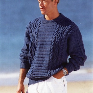 Könnte beinhalten: Ein blauer Strickpullover mit Zopfmuster und Rundhalsausschnitt. Der Pullover ist aus weichem, bequemem Material gefertigt und hat eine lockere Passform.