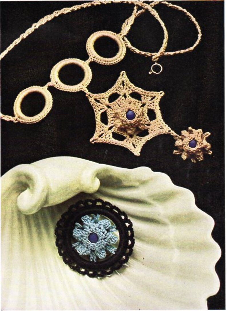 May include: A set of three crocheted necklaces with blue and brown beads. The necklaces are made with a beige yarn and feature a star, circle, and flower design.