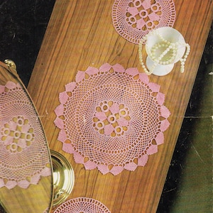 May include: Three pink crocheted doilies on a wooden surface. The doilies are circular and have a delicate, lacy design. The text "COATS Mercer-Crochet Design" is printed at the top of the image. The text "LEAFLET 960 PRICE 6d. WORKED IN COATS MERCER-CROCHET No. 40" is printed below the title.