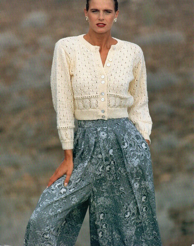 May include: A white crocheted cardigan with a button-up front and a floral print skirt.
