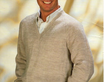 May include: A beige knitted sweater with a V-neck and long sleeves. The sweater is made of a soft, textured yarn.