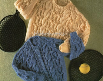 May include: Two knitted sweaters, one in a light cream color and one in a dark blue color, with a cable knit pattern. The sweaters are laid out on a green surface with two tennis rackets and a tennis ball.
