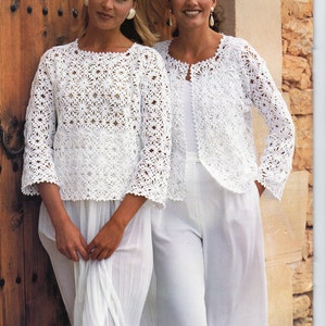 May include: Two women wearing white crocheted tops. The tops have a floral pattern and are open in the front. The women are standing in front of a wooden door.