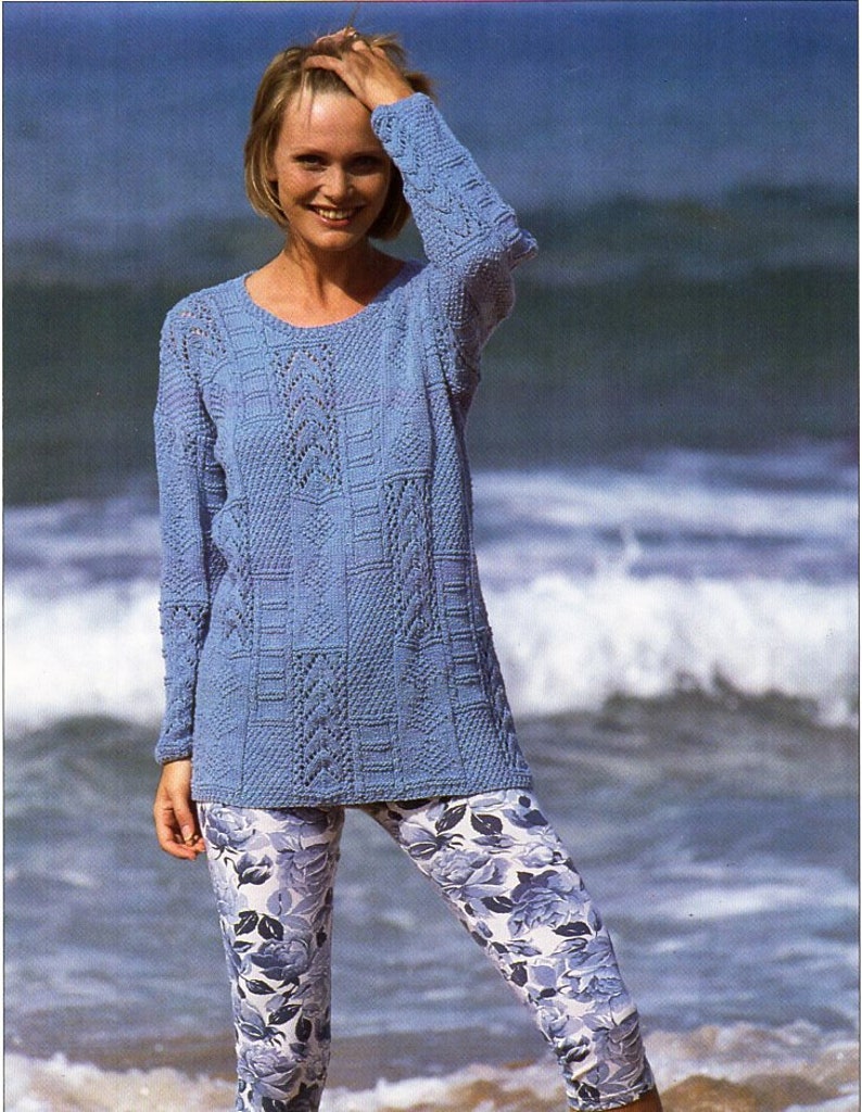 Puede incluir: Un su&eacute;ter azul de punto con un patr&oacute;n de encaje, usado con leggings de estampado floral. La modelo est&aacute; de pie en una playa.