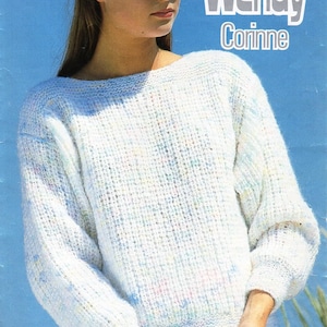 May include: A white knitted sweater with a speckled pattern. The sweater has a boat neck and long sleeves. The model is wearing a white sailor hat and a white skirt.