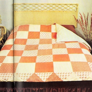 May include: A patchwork quilt with orange and white squares, on a bed with a wicker headboard. The quilt has a floral pattern on some of the squares.