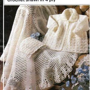 May include: A white crochet shawl, a white knitted cardigan, and a white crochet hat. The shawl and hat are trimmed with a white satin ribbon. The pattern is a simple, openwork stitch. The cardigan has a collar and button closure. The text on the page reads "Double knitting Crochet shawl in 4 ply Sizes 41-51 cms (16-20 inches) 425".